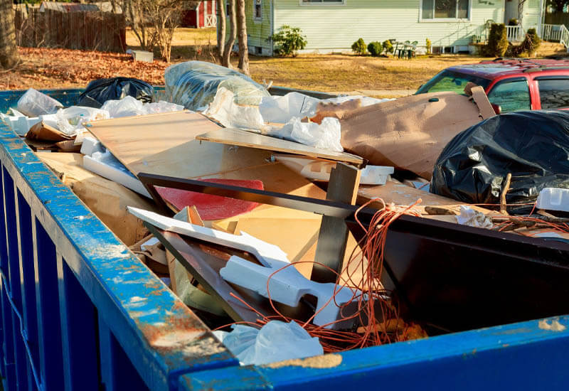 rental dumpster filled with trash and debris from a construction site